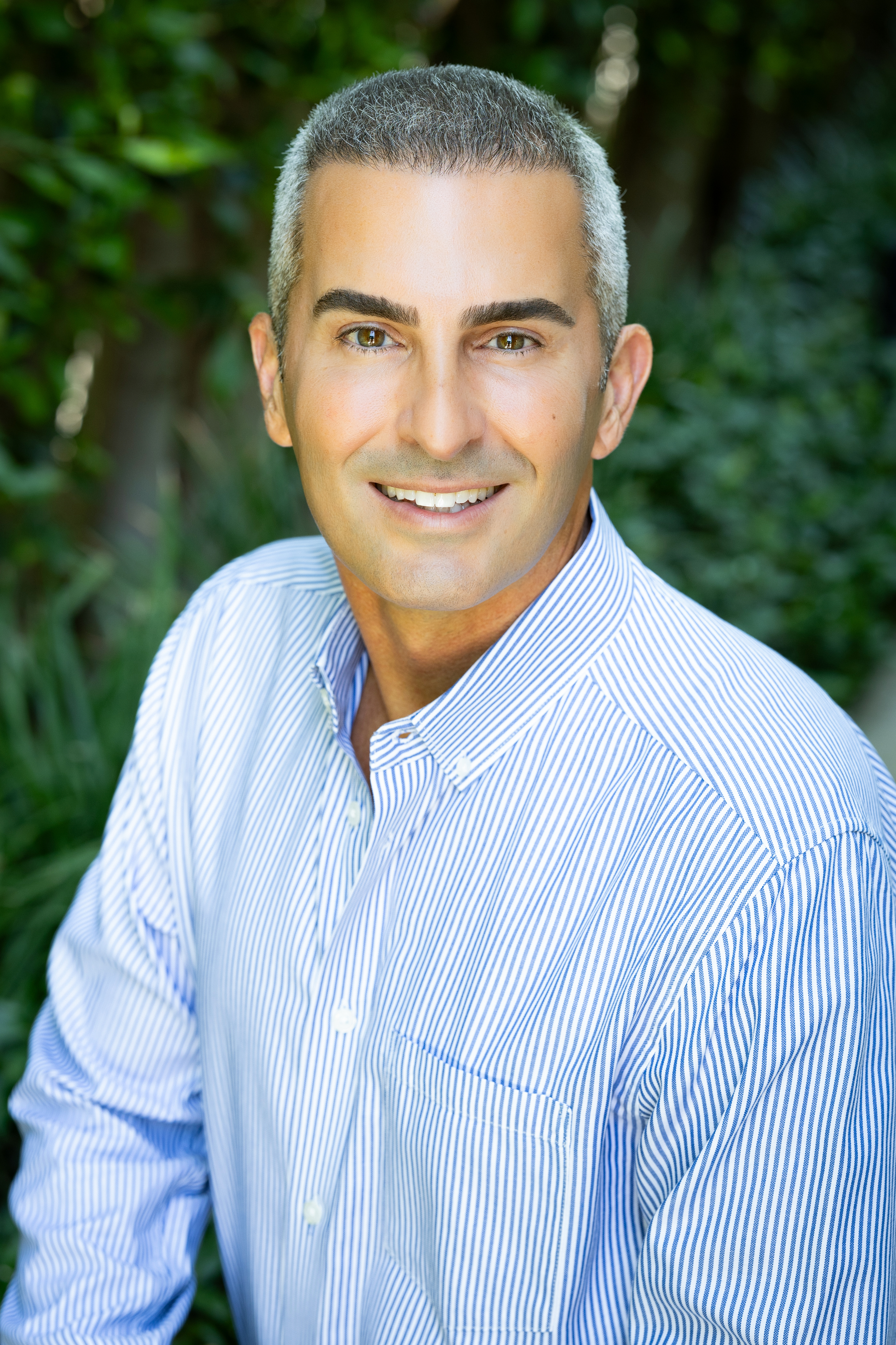 Dr. Shahin Ghadir smiling in a blue striped shirt