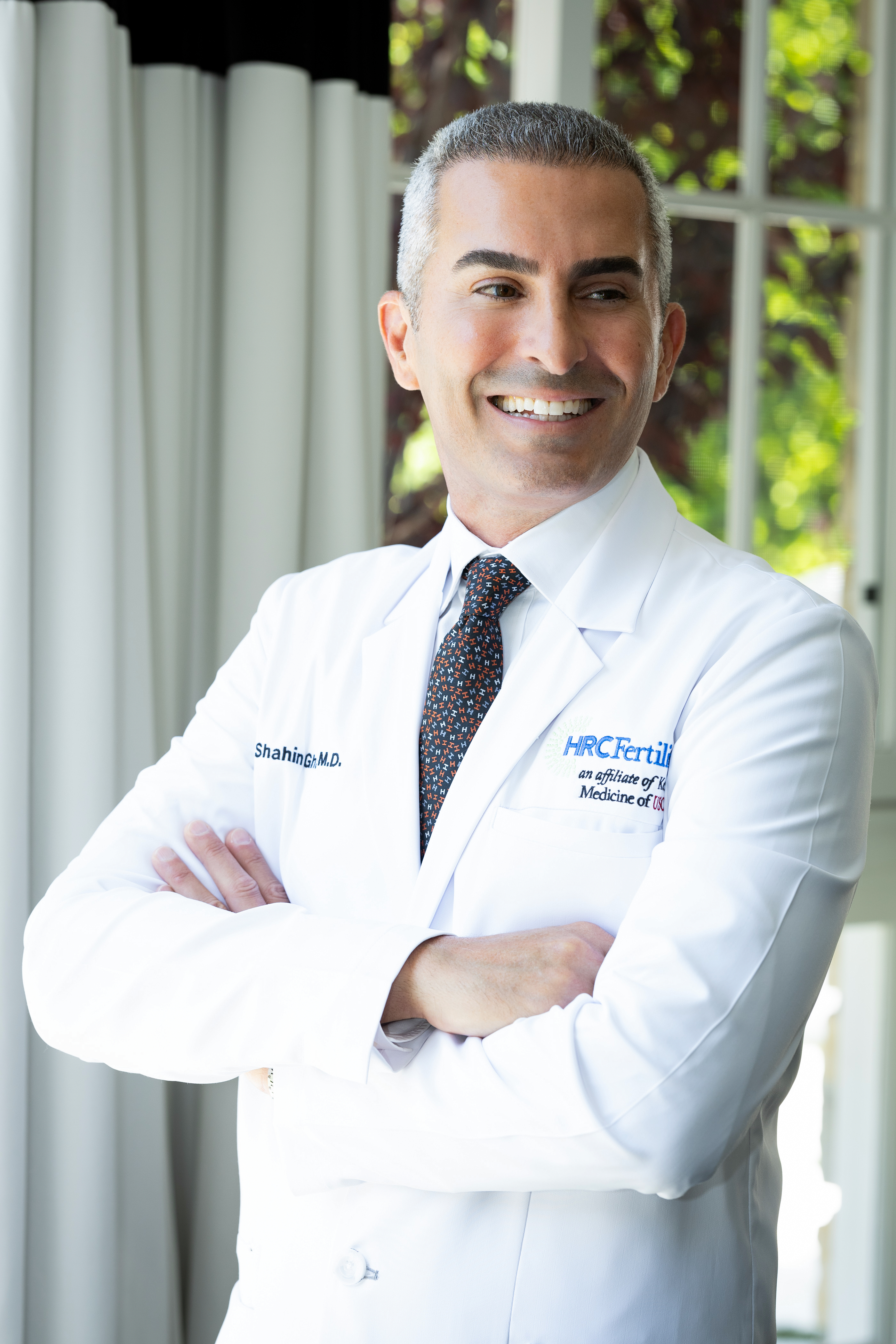 Dr. Ghadir with arms crossed wearing an HRC Fertility coat